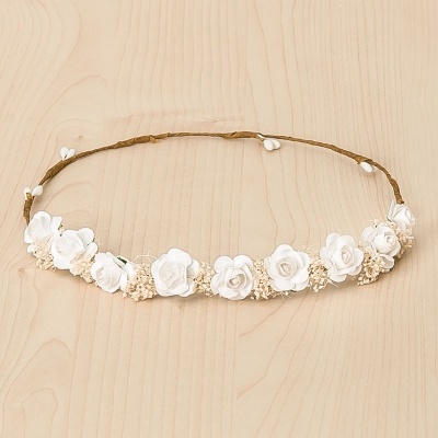 Tiara com flores artificiais brancas sobre fundo de madeira clara