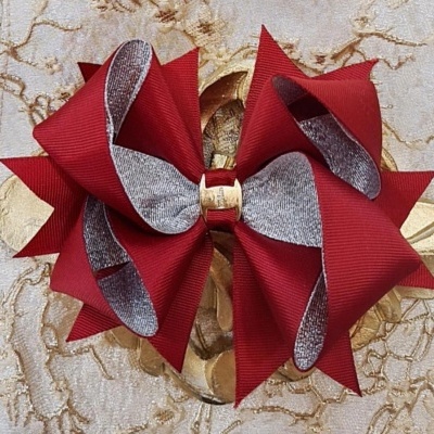 Laço decorativo vermelho e prateado sobre superfície bege com padrão dourado