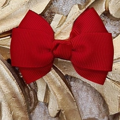 Laço vermelho de tecido sobre padrão floral creme e dourado