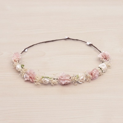 Coroa floral fina com flores rosa e brancas sobre fundo de madeira clara