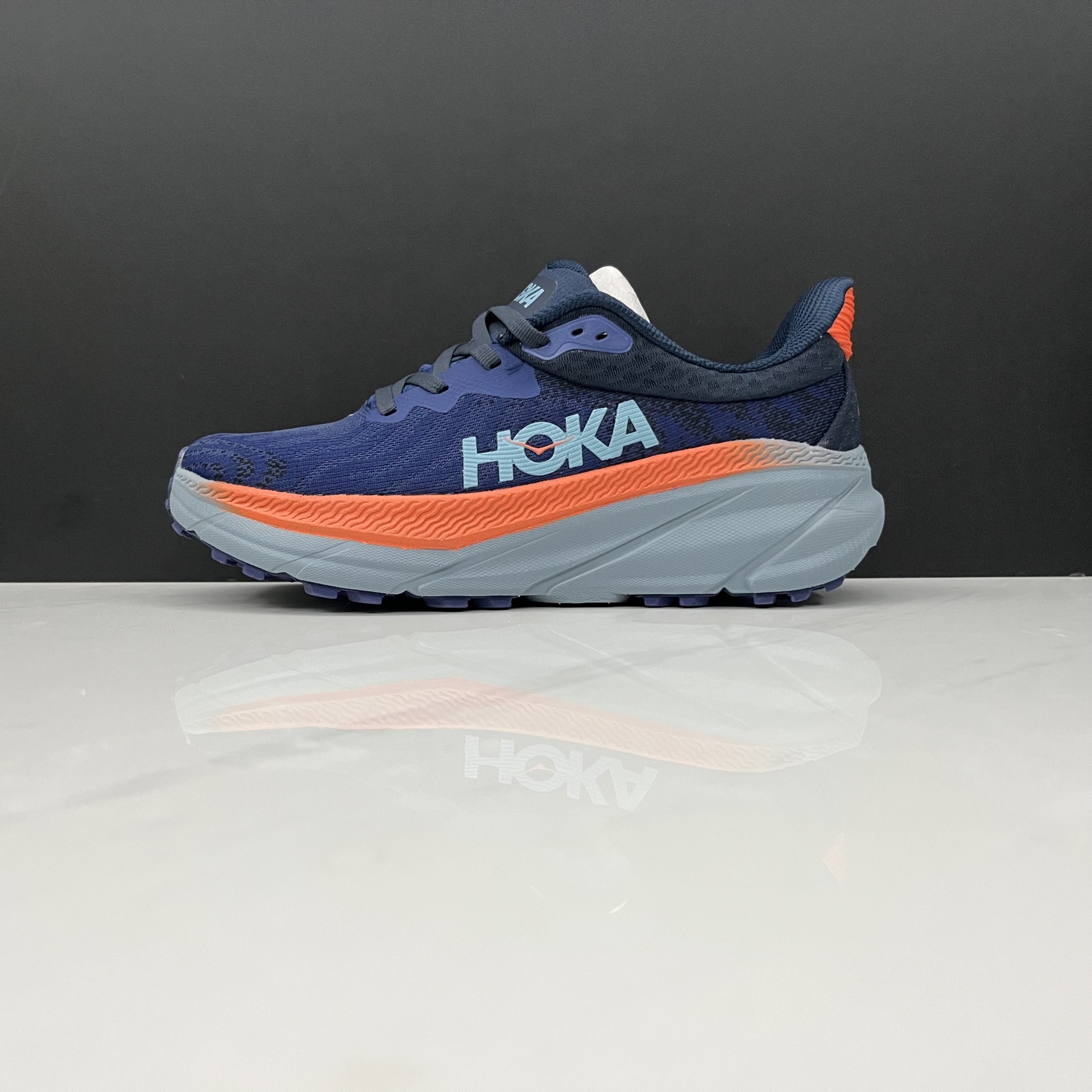 Ténis de corrida azul escuro com detalhes laranja e sola branca