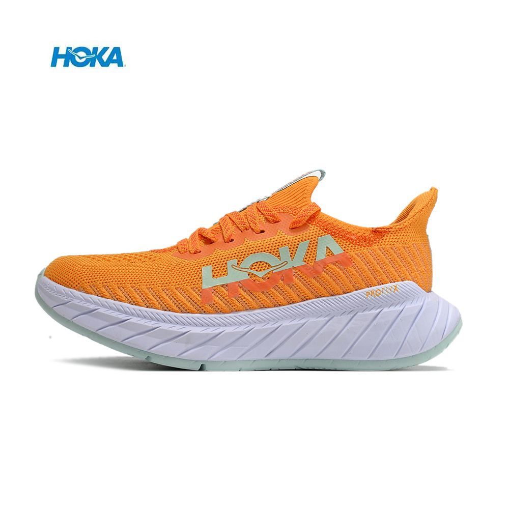 Tênis desportivo HOKA laranja com sola branca e logo na lateral.