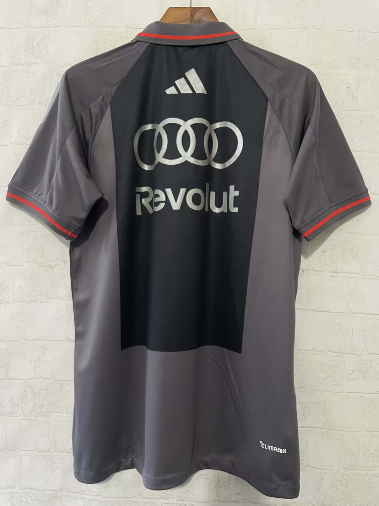 Camisola desportiva cinzenta e preta com logotipos Adidas, Audi e Revolut na parte de trás