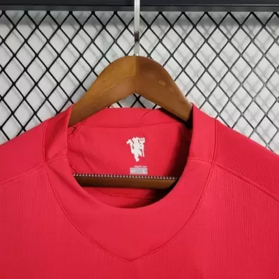 Camisola vermelha tamanho L com símbolo branco na gola pendurada num cabide