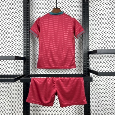Conjunto desportivo vermelho com padrão ondulado, t-shirt e calções, pendurados em suporte metálico com fundo em grelha
