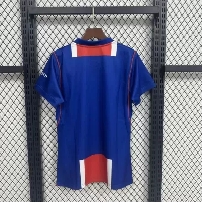 Camisola desportiva azul com detalhes vermelhos e brancos pendurada numa cabide