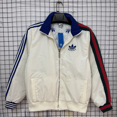 Casaco desportivo creme com gola azul e riscas nas mangas pendurado numa grade metálica