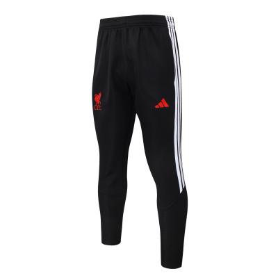 Calças desportivas pretas com riscas brancas e logos vermelhos do Liverpool FC e Adidas