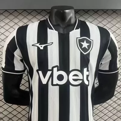 Camisola de futebol preta e branca com logótipos e brasão exibida em manequim