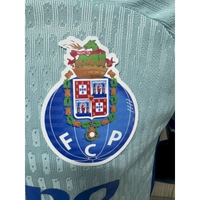 Emblema do FC Porto em tecido de camisola verde-azulada com textura