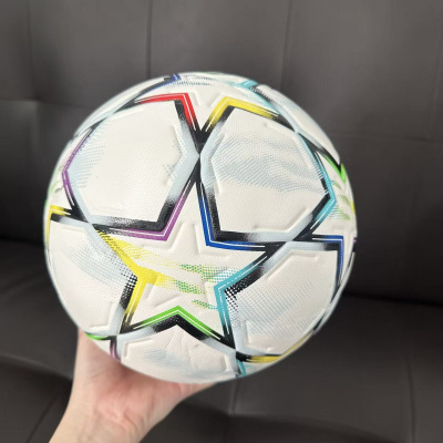 Bola de futebol branca com estrelas coloridas segurada por uma mão.