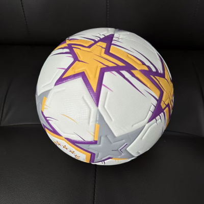 Bola de futebol branca decorada com estrelas coloridas sobre sofá preto