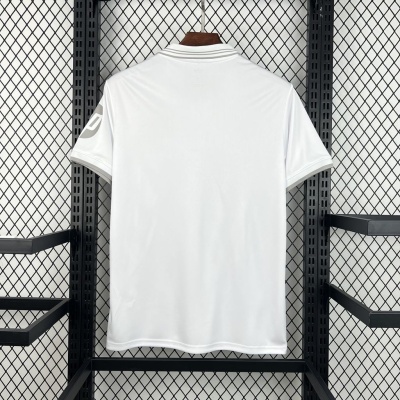 Camisola branca de manga curta pendurada num cabide com suporte metálico preto e fundo de rede.