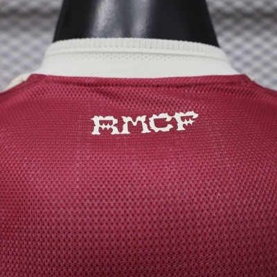 T-shirt vermelha de malha com gola branca e texto RMCF na parte traseira.