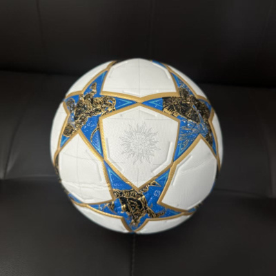 Bola de futebol branca com estrelas douradas e azuis sobre fundo preto