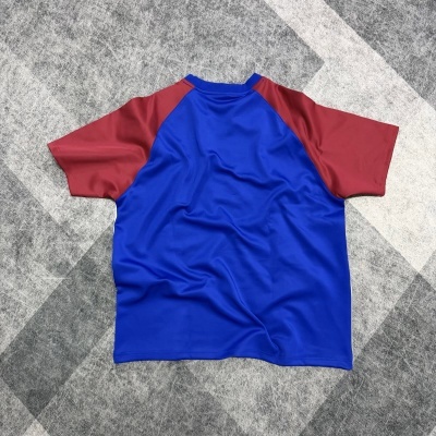T-shirt desportiva azul e vermelha sobre tapete cinza com padrão geométrico