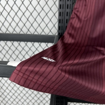 Detalhe de tecido desportivo vinho com riscas pretas e texto branco NB DRY