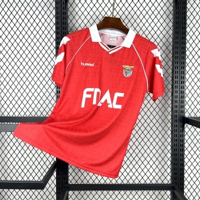 Camisola vermelha de futebol com gola branca e brasão do SL Benfica pendurada em cabide