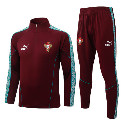 Conjunto desportivo bordô com detalhes azuis e logos Puma KING, com brasão da Federação Portuguesa de Futebol.