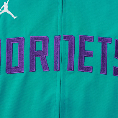Tecido verde-azulado com palavra HORNTS em roxo e logotipo Jumpman branco