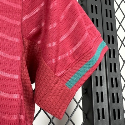 Manga curta vermelha com padrão texturizado e riscas cor-de-rosa, detalhe da barra com risca azul esverdeada e vermelha
