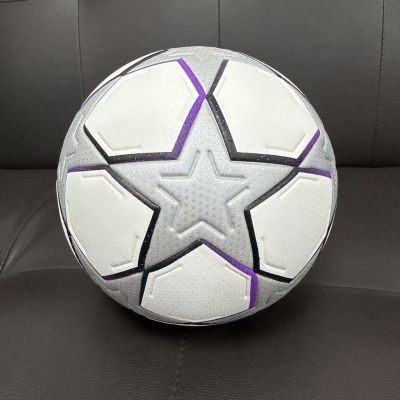Bola de futebol cinza claro com estrelas, roxo e branco num sofá escuro
