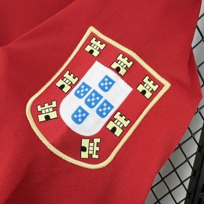 Tecido vermelho com brasão bordado contendo um escudo branco com cinco pequenos escudos azuis e moldura vermelha com castelos amarelos
