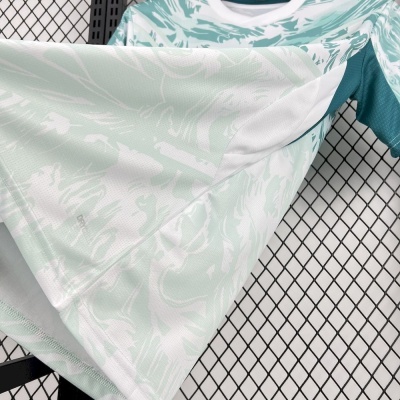 T-shirt desportiva branca e verde água com padrão abstrato exibida sobre rede metálica preta