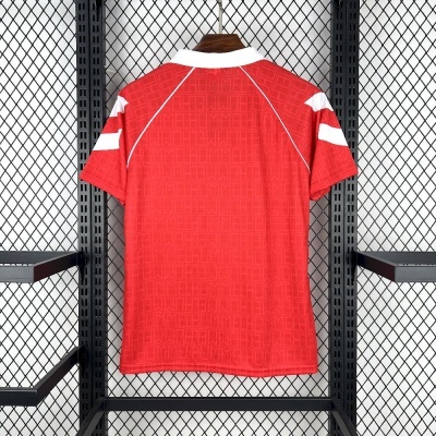 Camisola desportiva vermelha com padrão e gola branca pendurada num cabide