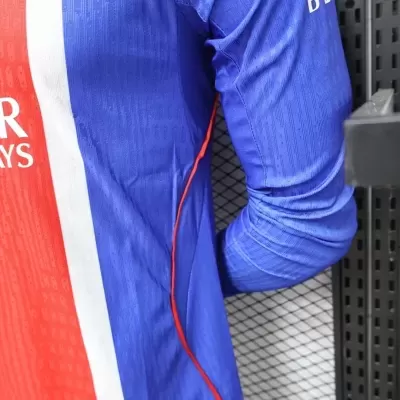 Camisola desportiva azul, vermelha e branca com detalhes e fundo metálico preto