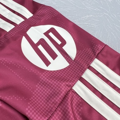 Pormenor de roupa desportiva vinho com riscas brancas e logo hp