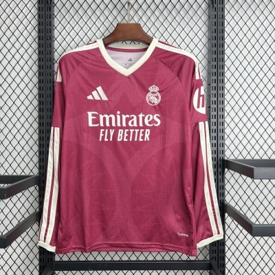 Camisola de futebol bordô de manga comprida com logos e texto, pendurada num cabide de madeira, fundo metálico com rede preta.