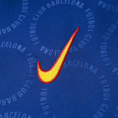 Tecido azul com padrão circular cinzento e símbolo Nike amarelo com contorno vermelho