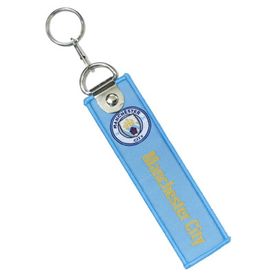 chaveiro tecido azul claro com logo e texto Manchester City e argola metálica