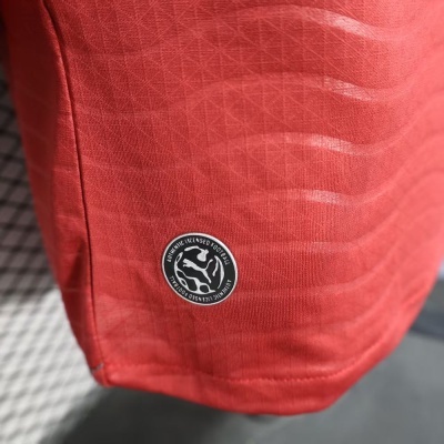 Tecido vermelho com padrão geométrico e etiqueta redonda preta com texto e logotipo branco