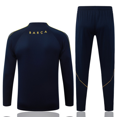 Conjunto desportivo azul escuro com riscas amarelas e palavra BARÇA nas costas da camisa.