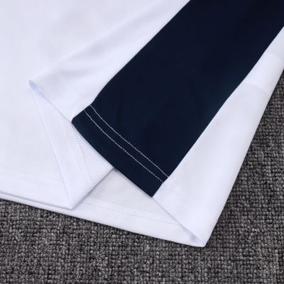 Peças de roupa brancas e azul escuro sobre tapete cinzento