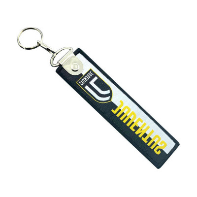 Porta-chaves retangular preto e branco com texto amarelo e emblema.