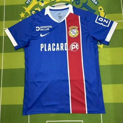 Camisola de futebol azul com faixa vermelha e branca e logos brancos
