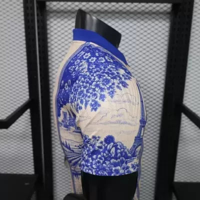 Polo azul e branco com padrão de paisagem e torre, em manequim preto
