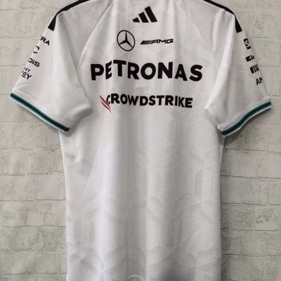 T-shirt branca com logótipos de marcas, em frente a parede de tijolo branco.