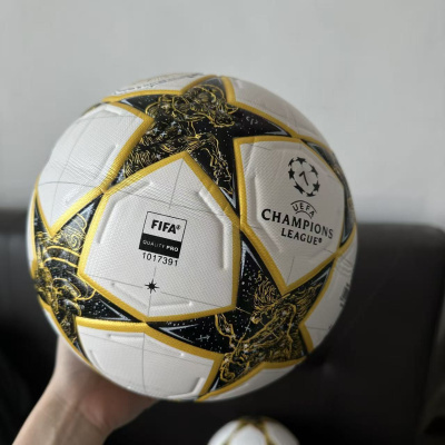 Bola de futebol branca com detalhes em preto e amarelo da UEFA Champions League.