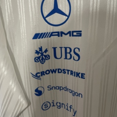 Logotipos azuis Mercedes-Benz, AMG, UBS, Crowdstrike, Snapdragon e Signify estampados em tecido branco listrado.
