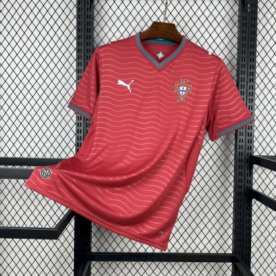 T-shirt desportiva vermelha com logos Puma e Federação Portuguesa de Futebol pendurada em cabide.