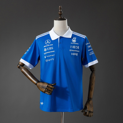 Polo azul com gola e bordas brancas, logos Mercedes AMG, UBS, PETRONAS e outros exposto em manequim.