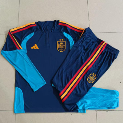 Conjunto desportivo azul com detalhes em vermelho, amarelo e azul claro, camisola e calças com emblemas e logo Adidas.