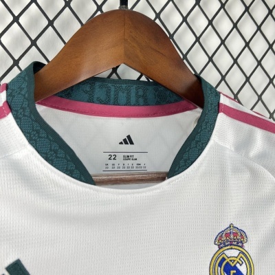 Camisola desportiva branca com detalhe em verde e rosa e emblema do Real Madrid