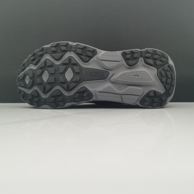 Sola de ténis cinza e preto com padrão de rasto em relevo e marca HOKA