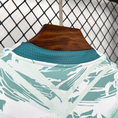 Peça de roupa com padrão verde e branco e gola verde escuro em cabide de madeira