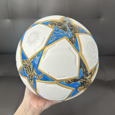 Bola de futebol branca com estrelas azuis e douradas e ilustrações a preto e dourado